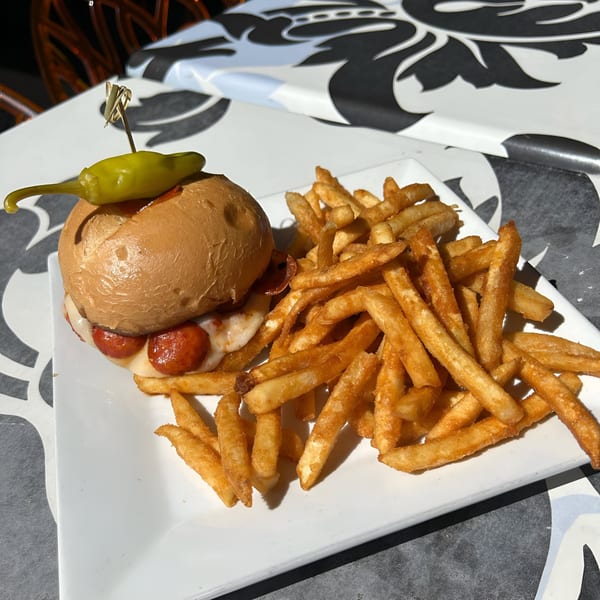 A Born And Raised Centennial pepperoni slider with melted cheese and a green pepper, served with fries.