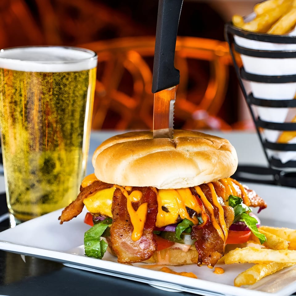 A bacon cheeseburger with fries and a beer, served at Born And Raised Centennial.
