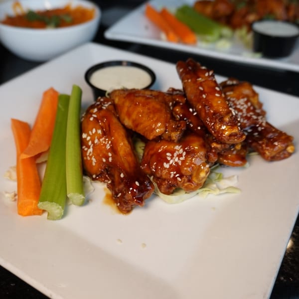 Born And Raised Centennial sports-bar wings, glazed with sesame seeds, served with carrots, celery, and ranch.