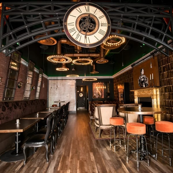 Born And Raised Centennial's interior features a large clock, chandeliers, brick walls, and diverse seating.
