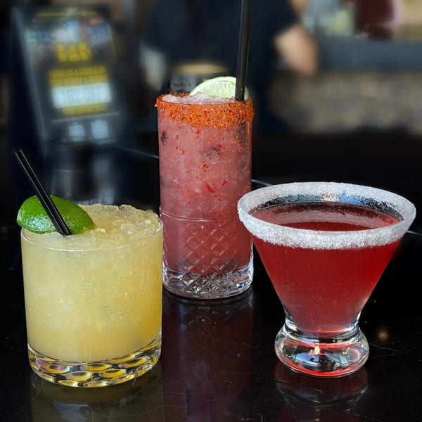 Three colorful cocktails, including a margarita and two red drinks, on a dark bar top at Born And Raised Centennial.