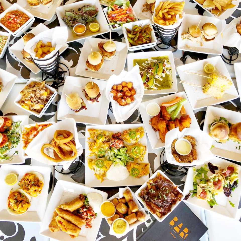 An overhead view of a table covered with various appetizers and small plates from Born And Raised Centennial.
